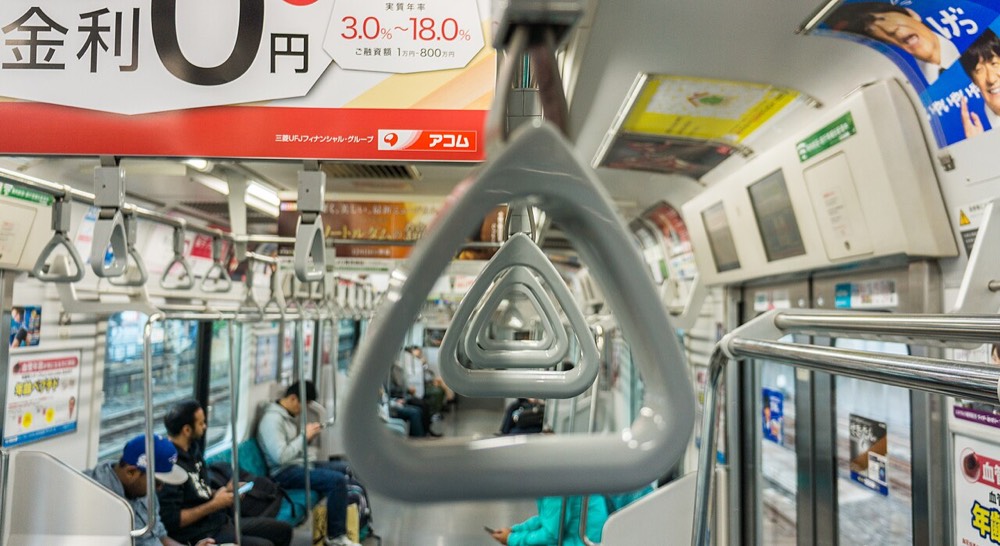 A commuter looking down at a smartphone on a Tokyo train