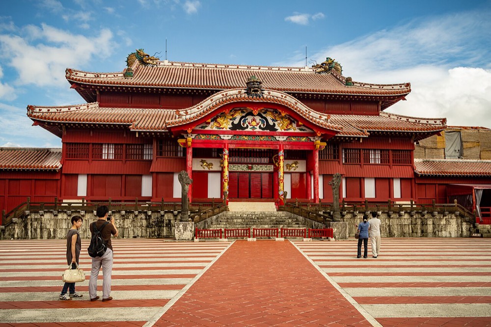 The vermilion-red exterior of Shuri Castle's main hall, with a wide plaza in front