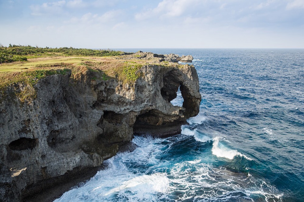 Coastal cliffs and grass at Cape Manzamo, with deep blue sea beyond