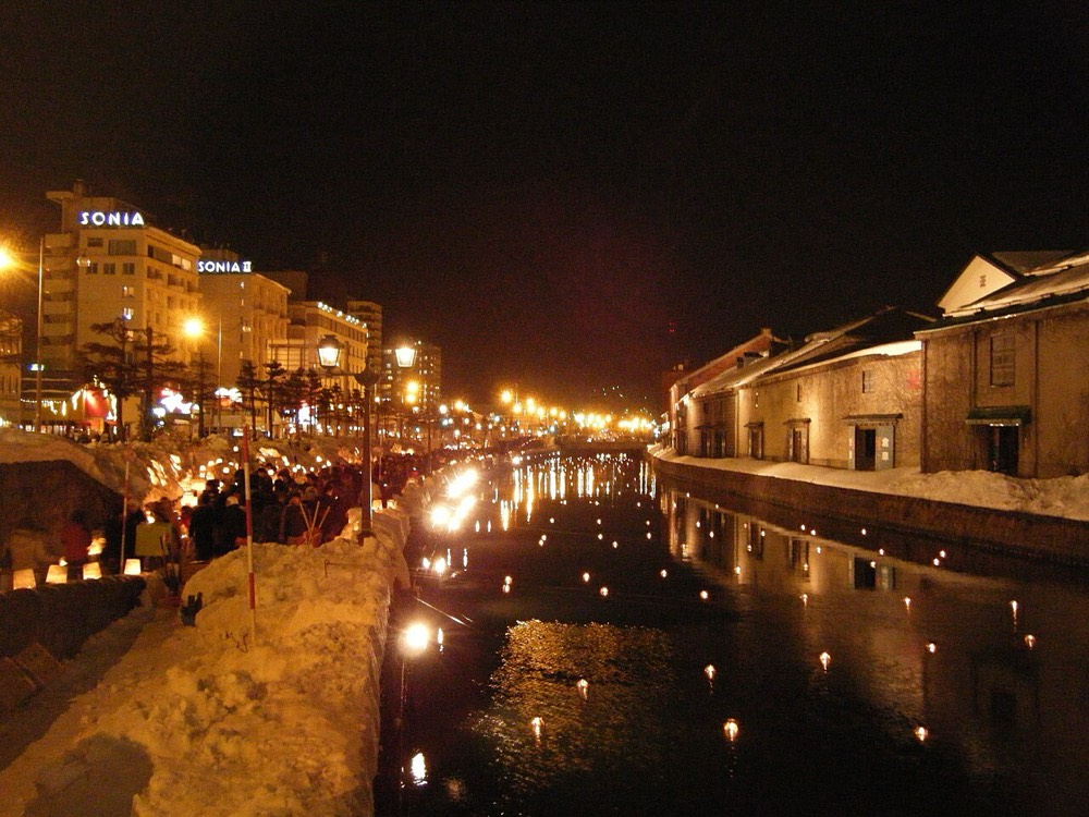 Candlelight reflected in the water along the canal during the Snow Light Path