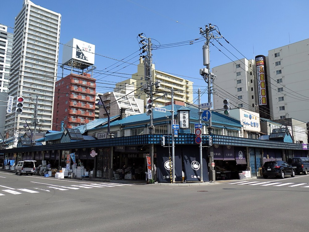 A shop on a corner of Nijo Market with noren curtains under a blue awning