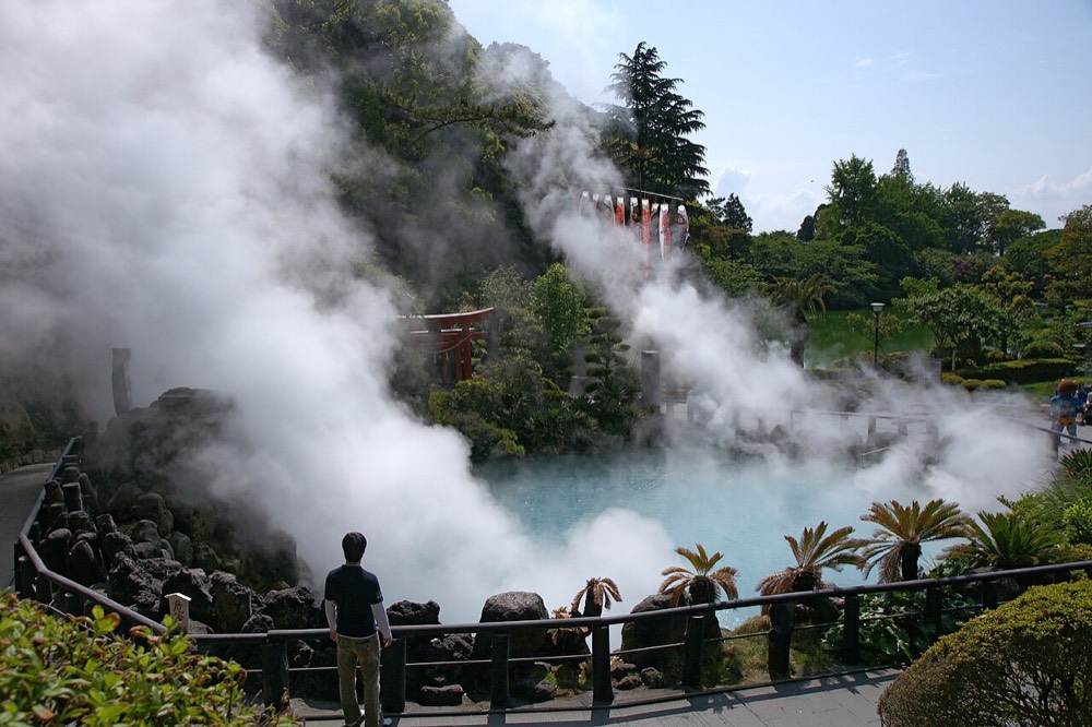 The blue hot spring surface of Umi Jigoku in Beppu, with white steam rising
