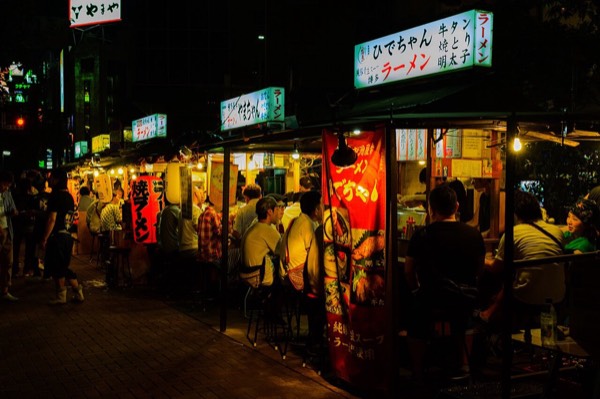 夜晚福岡中洲一字排開的屋台，招牌寫著拉麵、牛舌與明太子，是福岡美食推薦必訪的路邊攤
