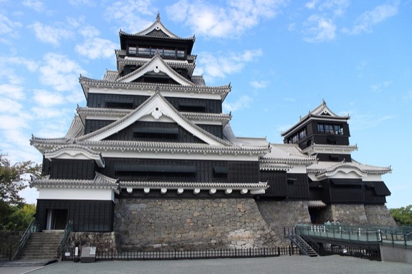 藍天下黑白相間的熊本城大天守與小天守，以及高聳的武者返石垣，熊本景點代表
