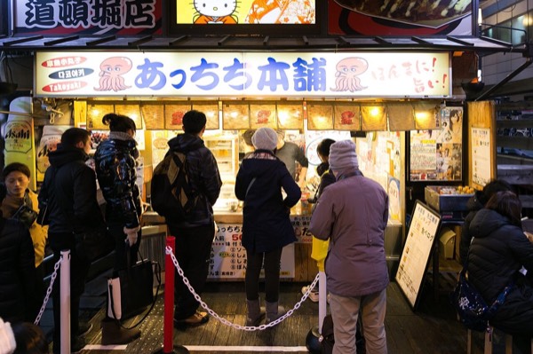 大阪美食代表道頓堀章魚燒攤前排隊的人潮與招牌