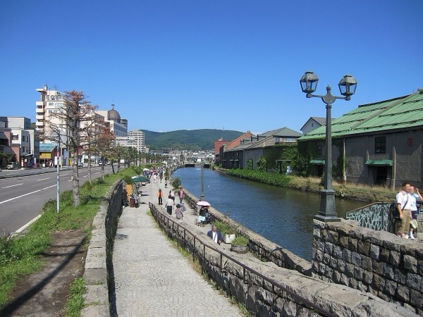 晴天下小樽運河旁的石造倉庫與步道瓦斯燈，小樽一日遊必訪景點