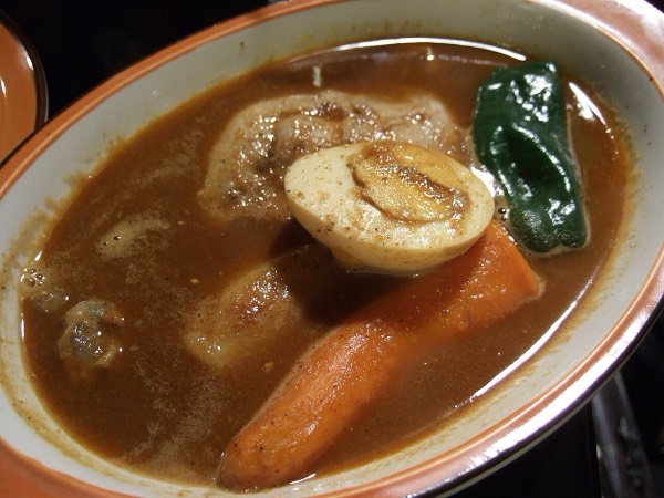 札幌湯咖哩，湯汁中放著雞腿、水煮蛋、紅蘿蔔與青椒等大塊食材